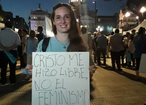 Courtesy of Belu Lombardi Belu Lombardi holds a sing reading "Feminism didn't set me free, Christ did"