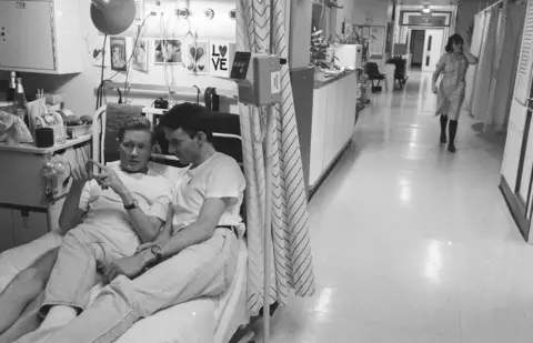 Gideon Mendel A couple share a bed together in hospital.