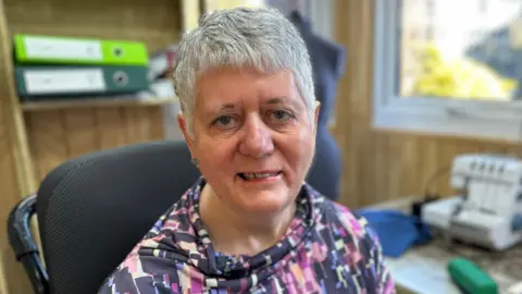 Sheila Hawkins looking at the camera. She has short grey hair and is wearing a patterned top