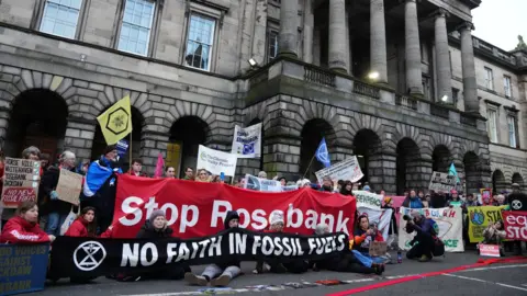 PA Media Protestors holding anti-fossil fuel banners gather under the colonnades of the Court of Session building. One reads 'Stop Rosebank'.