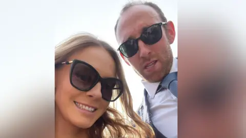 James Rogers/PA A close up selfie of James and Ellie, wearing sunglasses and dressed up as though going to a wedding. James wears a white shirt with blue tie and a smart jacket.
