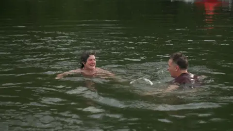 Two swimmers talk to each other in the River Teme.