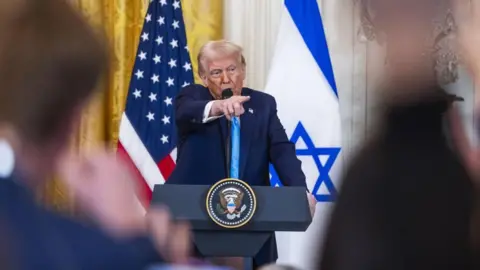 EPA Donald Trump di podium di depan bendera AS dan Israel selama konferensi pers 