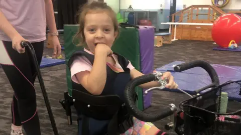 PA Five-year-old Ava Begley smiles as she is pushed in a three-wheeled scooter
