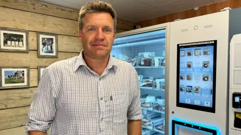 Farmer Tom Cooke standing in front of the beef vending machine on his farm.