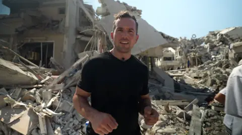 BBC Middle East Correspondent Hugo Bachega stands amongst rubble in Rishon LeZion, Israel