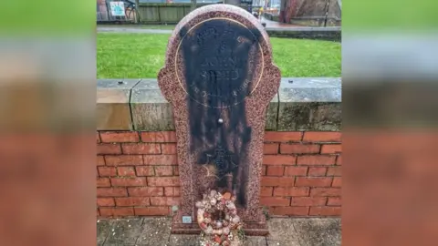 The memorial stone to Sgt John Speed showing black paint sprayed on the stone. 