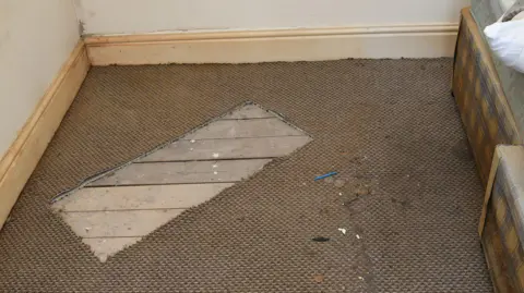 Police handout Rectangular piece of carpet beige carpet cut out of the floor in a room at a house.