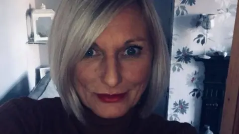 Family handout Sam Carter wearing a black top standing in her lounge