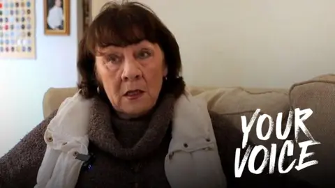 Eileen Jordan sits on her sofa