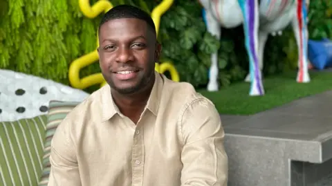 Damion Bailey Damion Bailey in beige shirt sitting in a garden