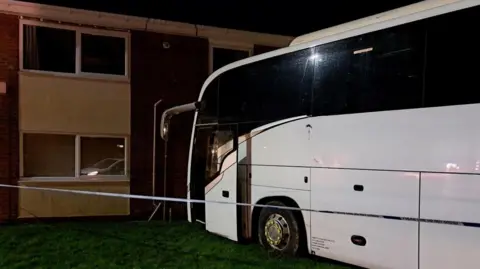 Northumbria Police A white coach on a patch of grass right up against a two-storey building