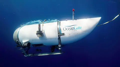 A submersible vessel with the name OceanGate written on its side is seen underwater.