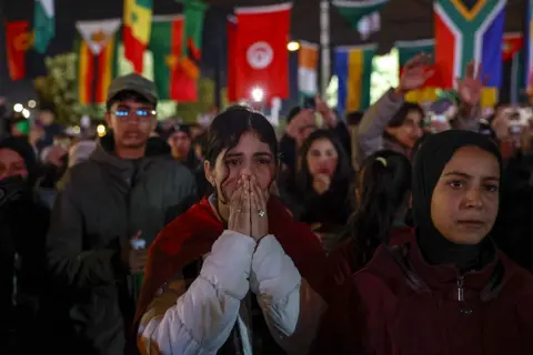 ANP via Getty Images A Moroccan fan has her hands clasped in front of her face. Other fans are around her looking sad.