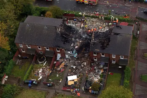 PA Media An aerial view of a row of homes on Violet Close, Newcastle, which were destroyed by an explosion. The houses on the far left and right of the row are still standing, while properties in the middle have been reduced to rubble. 