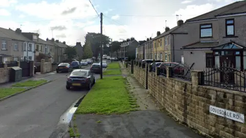 Google View of Dovesdale Road in Bradford, with terraced houses and cars on either side.