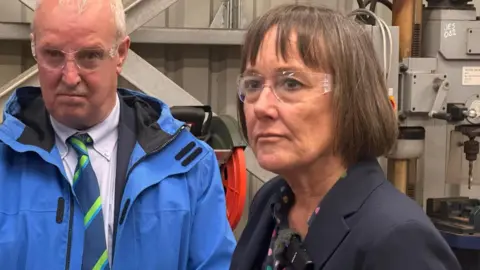 BBC Jo Stevens wearing protective goggles while visiting an engineering firm.
