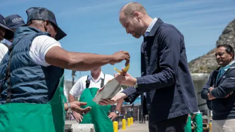 Getty Images Prince of Wales is handed a fish as he speaks to a local fisherman in Cape Town