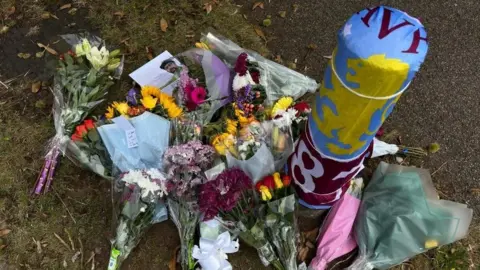 Flowers around a post and the post has been covered with an Aston Villa flag of blue, claret and gold. 