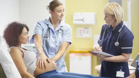 Getty Images A midwife checks over a patient