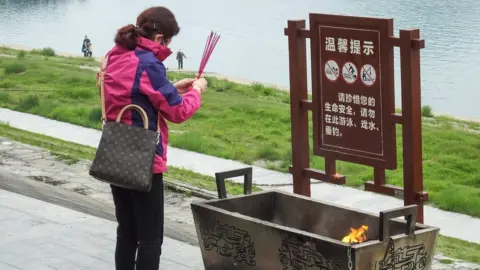 AFP A woman burns incense ahead of the tomb sweeping festival