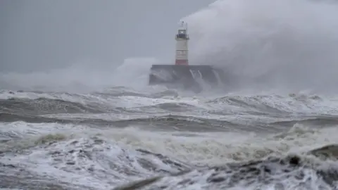 PA Media A lighthouse amid waves at Newhaven in East Susses during Storm Ciara