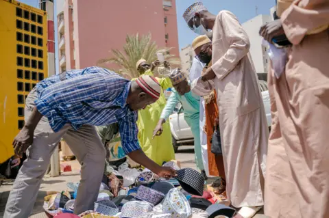 AFP Men buy hats in Dakar, Senegal - Friday 29 April 2022