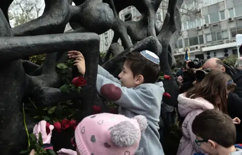 AFP A child lays roses at the Holocaust Memorial monument in Thessaloniki