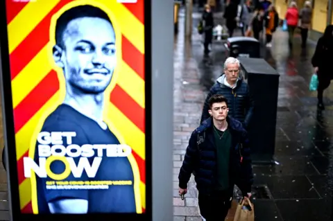 Getty Images vaccine booster poster in the street with people walking by