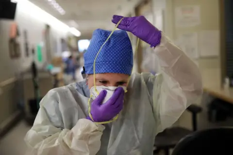 Getty Images Nurse puts on a mask