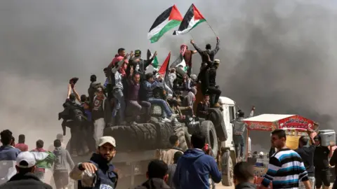 AFP Palestinian men wave flags during a protest east of Gaza City on 6 April 2018