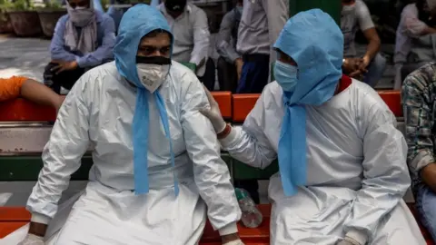 Reuters Two men sit together in PPE