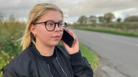 Woman holding mobile phone by roadside