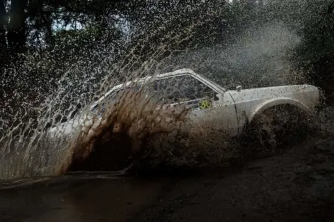 AFP A rally car splashes water as it drives over a stream.
