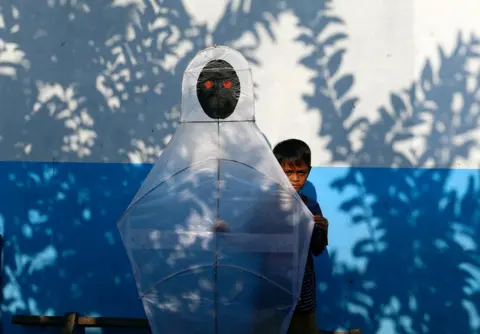 AJENG DINAR ULFIANA/Reuters A child carries a kite depicting a ghost