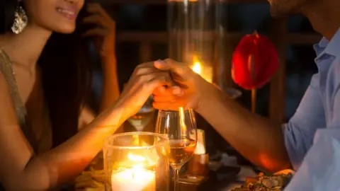 Getty Images Couple holding hands at candlelit table