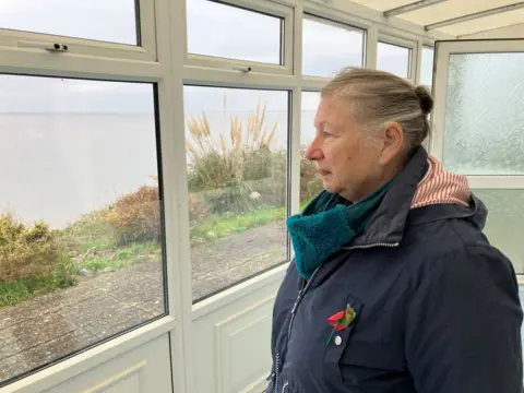 Guy Campbell/BBC Jacky Campling looking out at the view from her family chalet in Pakefield
