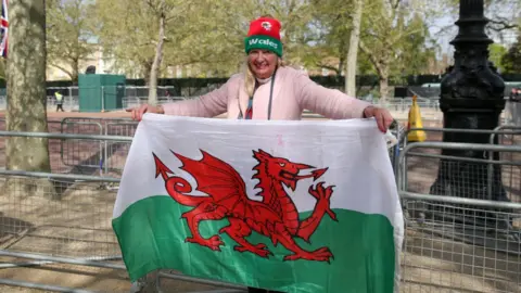 Getty Images A royal fan holds aloft the Welsh flag outside Buckingham Palace