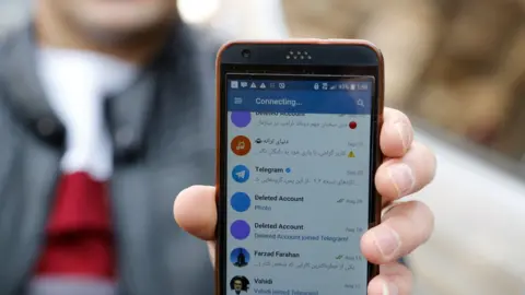 EPA An Iranian man shows his mobile phone attempting to connect to social media channels in Tehran (2 January 2018)