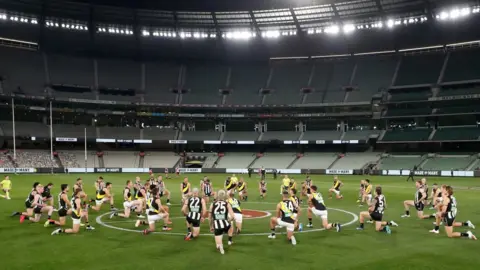 Getty Images Players from the Collingwood and Richmond AFL teams take a knee prior to a match in June 2020 as a gesture of support for the Black Lives Matter movement