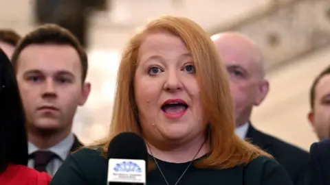 PA Media Naomi Long pictured speaking at a microphone