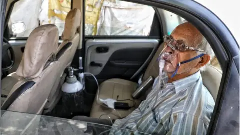 Sumit Kumar Sushil Kumar Srivastava was photographed sitting in his car, strapped to an oxygen cylinder