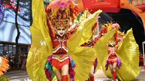 Getty Images Wearing colourful outfits, several participants from the Granada Masskara Dance group take part in a parade in Hong Kong