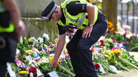 Getty Images A police officer places flowers on behalf of a member of the public in the garden area outside the Palace of Holyroodhouse