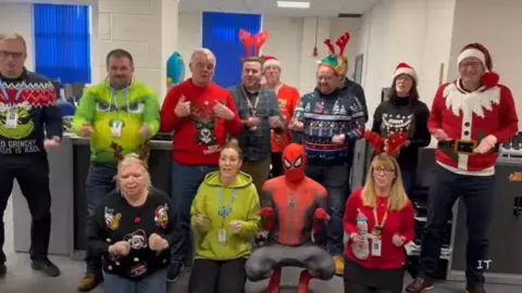St Andrew's Healthcare Staff , some in Christmas hats and one dressed as Spiderman, signing in Makaton
