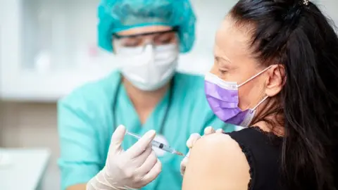 Getty Images Flu jab being administered by health worker in personal protective equipment