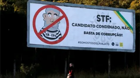 Reuters A woman walks past a billboard which reads: "No to convicted candidates! Stop corruption!".