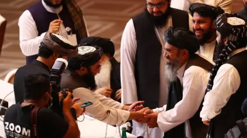 Reuters Taliban delegates shake hands during talks with the Afghan government in Doha, Qatar. Photo: 12 September 2020