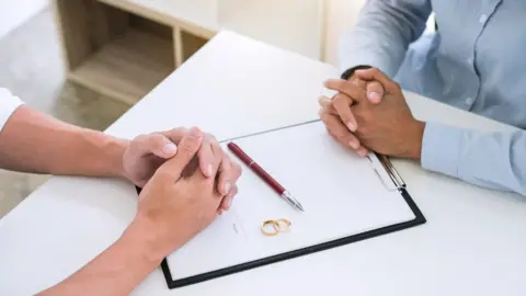 Getty Images Couple signing divorce paperwork