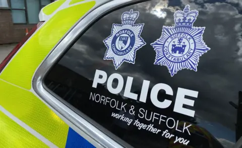 Ben Parker/BBC A police car with the badges for both Norfolk and Suffolk police forces on the window